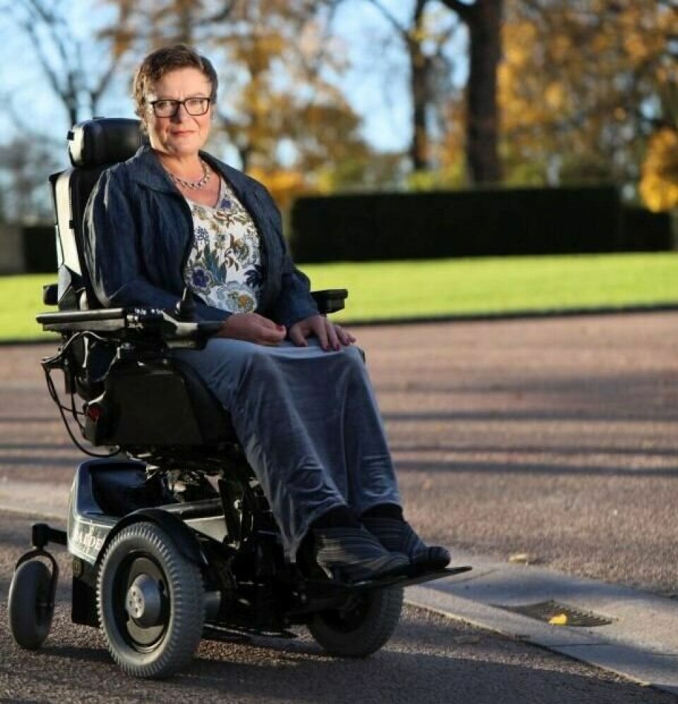 Tove Linnea Brandvik Kvinne med skandisnavisk utseendet sitter i rullestol, bruker briller, smiler til kamera.