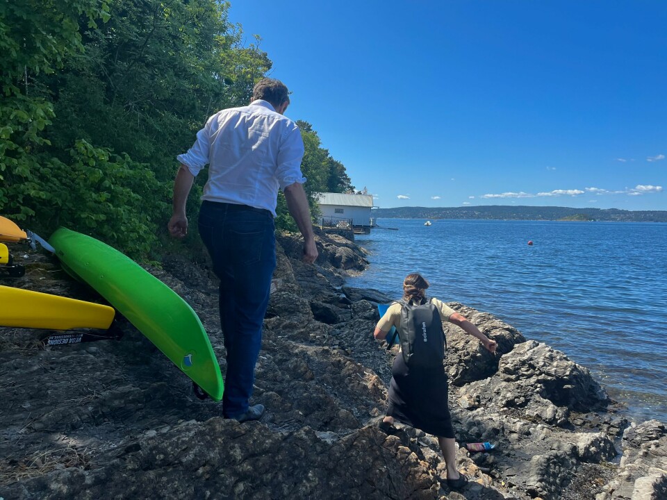 Byråd Arild Hermstad på tur langs nordsiden av Ormøya. Målet er å se gjerdet som stenger for fri ferdsel. Byråd Arild Hermstad går på skjær for å komme seg frem til et gjerde mot slutten av bildet. Ved siden av han ligger to kanoer, en grønn og en gul. Foran går prosjektleder Lena Catrine Amdal.