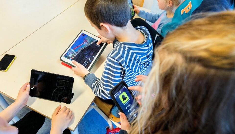 Illustrasjonsfoto. Bildet viser barn som holder på med mobiler og ipader i et klasserom.