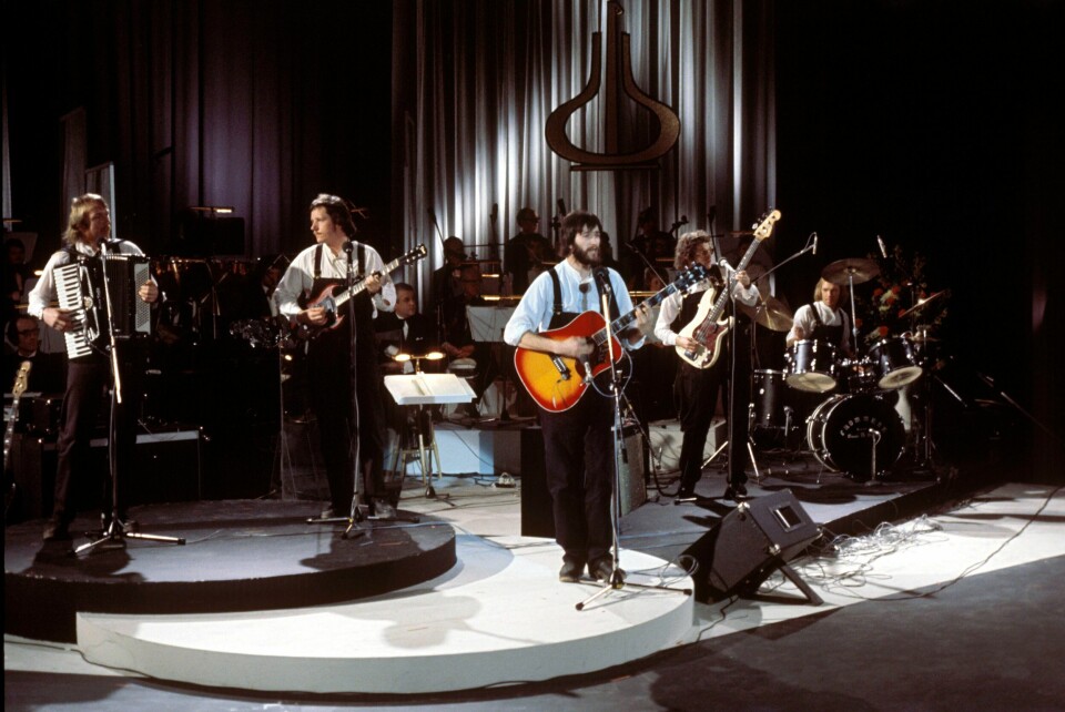 Hans Rotmo og Arbeidslaget hass K. Vømmølbakken under Spellemannprisen i 1977. Hans Rotmo er klart med et nytt Vømmøl Spellmannslag for jubileumsåret 2024. Her er han fotografert med akustisk gitar under utdelingen av Spellemannprisen i 1977 sammen med Arbeidslaget hass K. Vømmølbakken. Laget bygde videre på Vømmøl-ideologien og Vømmøl Spellmannslag. Foto: NTB
