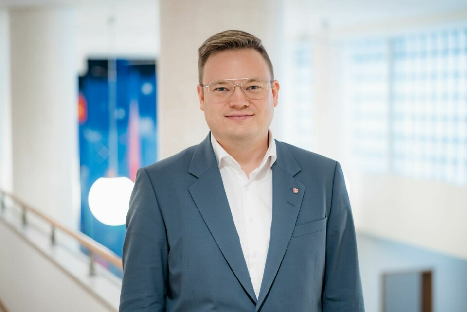 Even Aleksander Hagen, statssekretær (Ap). Ung mann med blå dress står i kontoromgivelser. Han har briller og har satt sitt lysebrune hår litt til sida. Han smiler litt.