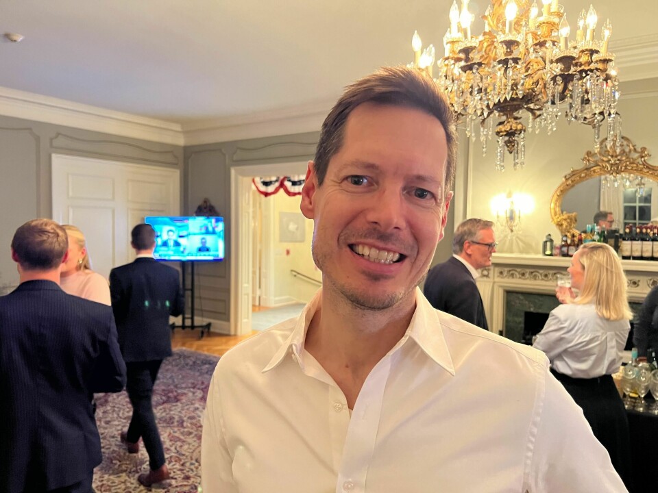 Hans Høegh. Mann smiler kleint med hvit skjorte. Svær lampe i bakgrunnen.