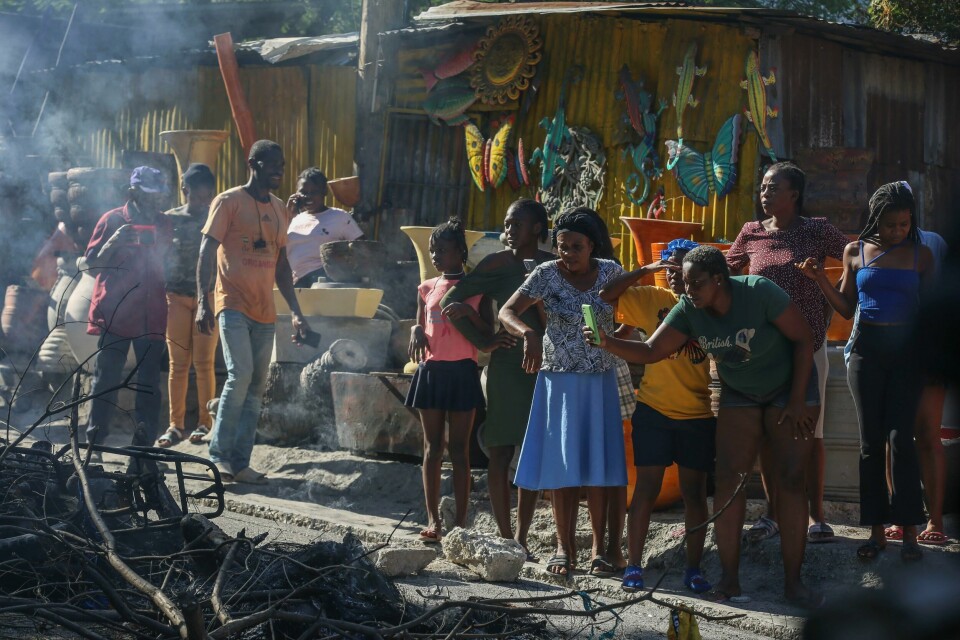 En kvinne filmer det som skal være drepte gjengmedlemmer som så er satt i brann. Rundt 30 mistenkte gjengmedlemmer ble drept av politi og innbyggere i Port-au-Prince-forstaden Petrion-Ville Petion-Ville natt til tirsdag og tirsdag. En kvinne filmer det som skal være drepte gjengmedlemmer som så er satt i brann. Rundt 30 mistenkte gjengmedlemmer ble drept av politi og innbyggere i Port-au-Prince-forstaden Petrion-Ville Petion-Ville natt til tirsdag og tirsdag. Foto: Odelyn Joseph / AP / NTB