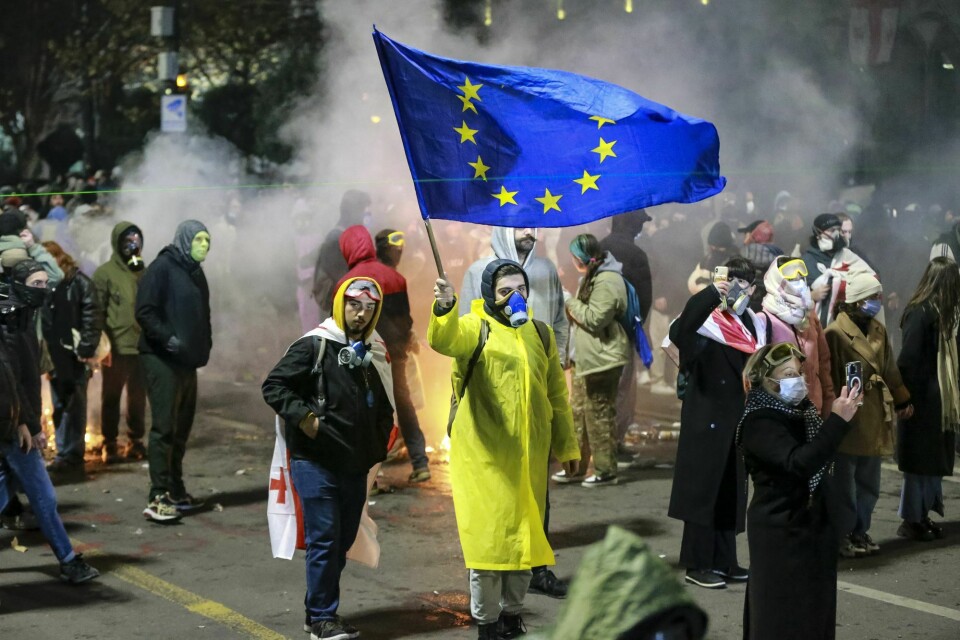 Demonstranter med EU-flagg utenfor nasjonalforsamlingen i Tbilisi, der demonstrasjonene mot regjeringens beslutning om å legge medlemskapsforhandlinger på is, fortsetter. Demonstranter med EU-flagg utenfor nasjonalforsamlingen i Tbilisi, der demonstrasjonene mot regjeringens beslutning om å legge medlemskapsforhandlinger på is, fortsetter.