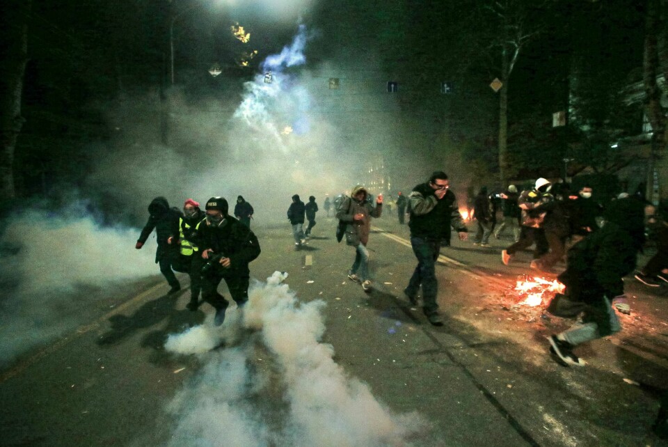 Demonstranter løper unna politiet utenfor nasjonalforsamlingen i Georgias hovedstad Tbilisi natt til søndag. Bildet viser demonstranter som løper fra politi i Georgia. Foto: Zurab Tsertsvadze / AP / NTB