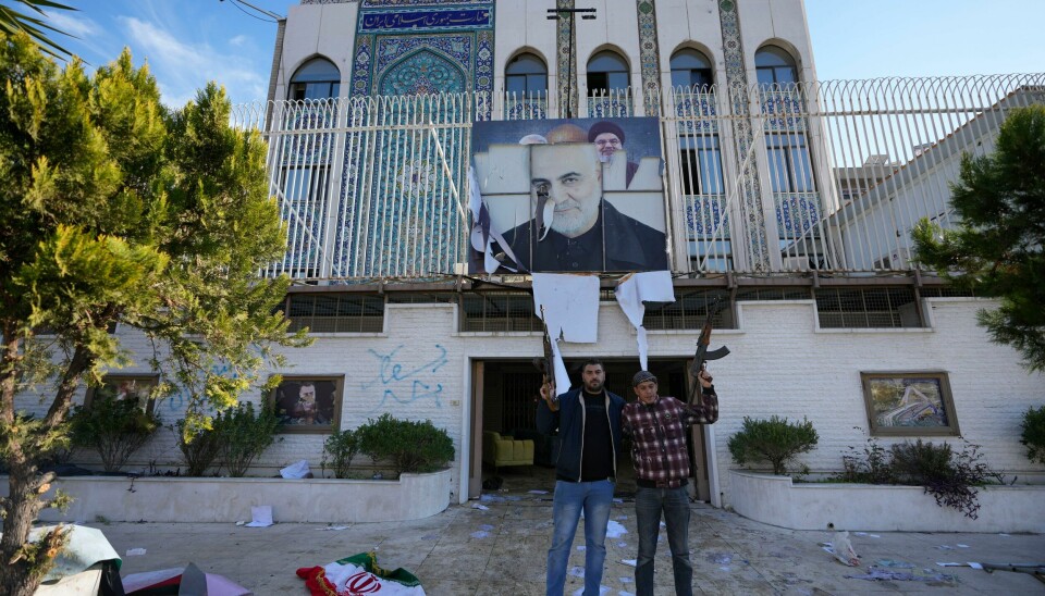 Syriske opprørssoldater foran den ødelagte inngangen til Irans ambassade i Damaskus etter at den ble stormet og delvis rasert søndag. Syriske opprørssoldater foran den ødelagte inngangen til Irans ambassade i Damaskus etter at den ble stormet og delvis rasert søndag. Foto: Hussein Malla / AP / NTB