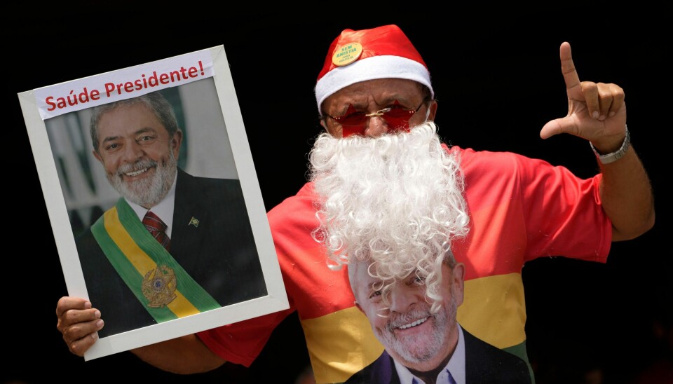 En av Lulas tilhengere med julenissekostyme og en plakat der presidenten ønskes god helse. En av Lulas tilhengere med julenissekostyme og en plakat der presidenten ønskes god helse. Foto: Eraldo Peres / AP / NTB
