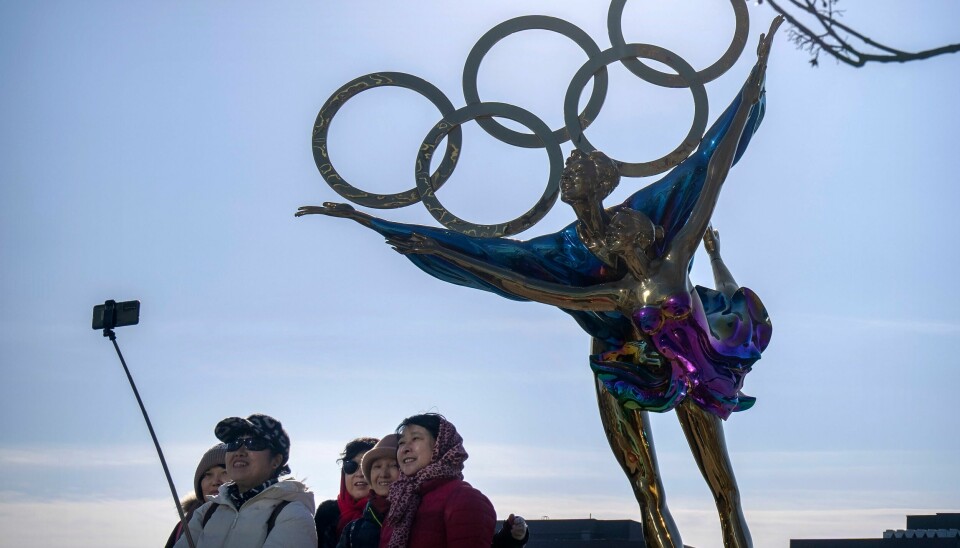 Folk tar selfie foran en statue med de berømte OL-ringene i Beijing. Arrangørene av Beijing-OL tar smitteverngrep. Foto: Mark Schiefelbein / AP / NTB