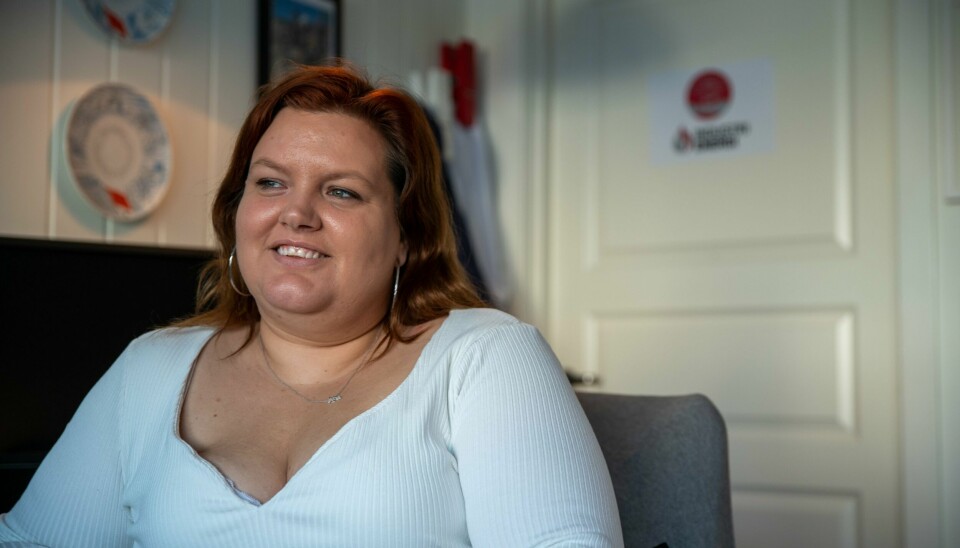 PAUSE: Teknisk operatør Siw-Hege Christiansen ved Fresenius Kabi i Halden mener ulempene de opplever ved å aldri vite når pausen kan tas, bør kompenseres med betalt spisepause. Kvinne i hvit genser smiler, halvportrett