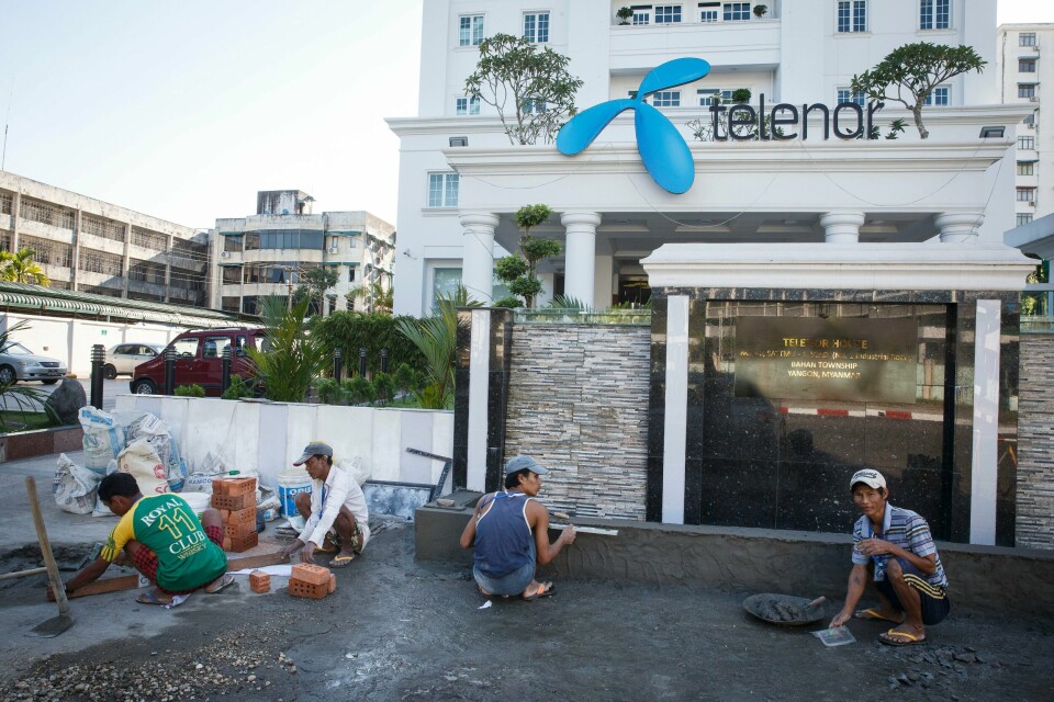 Håndverkere i arbeid utenfor Telenors hovedkontor i Yangon før det norske statsbesøket med næringsministeren og kongeparet i 2014. Nå skal Telenor Myanmar selges, men hvis selskapet ikke sletter data om 18 millioner kunder vil demokratiforkjempere i landet settes i livsfare, skriver artikkelforfatterne. Telenor Myanmar