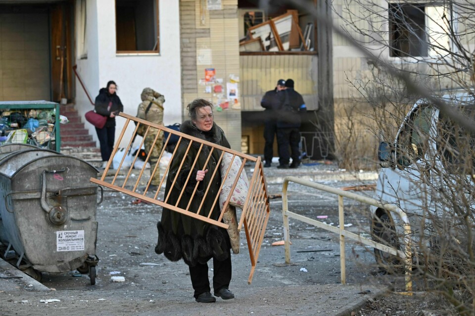 En kvinne bærer deler av en barneseng ut av en ødelagt boligblokk etter at den ble truffet av en rakett i Kyiv. En kvinne bærer deler av en barneseng ut av en ødelagt boligblokk etter at den ble truffet av en rakett i Kyiv.