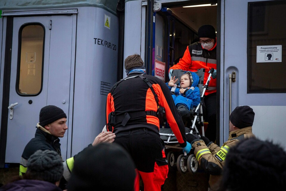 Et funksjonshemmet barn fra Ukraina hjelpes om bord i et spesialtog i Warszawa. Men rapporter fra Ukraina melder at brorparten av landets 2,7 millioner funksjonshemmede ikke kommer seg i sikkerhet, skriver artikkelforfatterne. Ukraina, funksjonshemmede