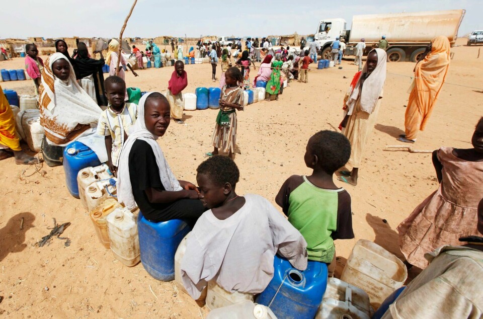 Over seks uker etter at det ble bekreftet hungersnød i Zamzam-leiren i Darfur har bare noen få lastebiler med mat og annen nødhjelp nådd fram til leiren. Det er fullstendig uakseptabelt, skriver forfatterne av innlegget. Bildet viser flyktninger i kø for drikkevann. Zamzam flyktningleir, Darfur, Sudan