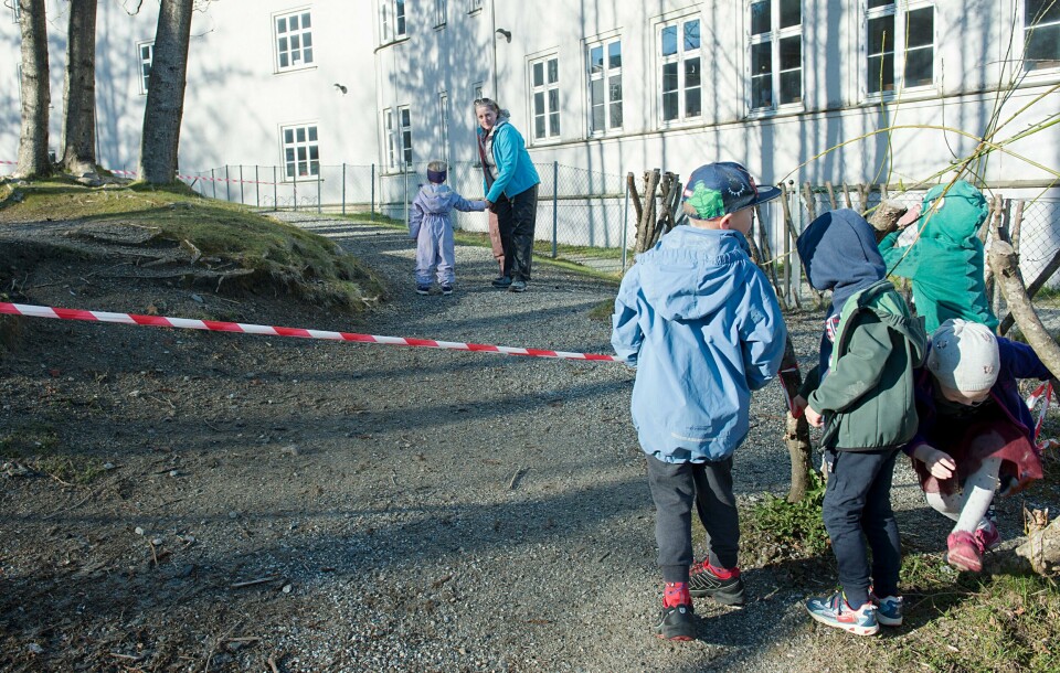 «Barneombud Inga Beyer Engh har nylig skrevet brev til alle de involverte departementene der hun ber om at tiltak for barn og unge blir lettet på.» Bergen 20200420. Barnehagebarn står og venter ved sperrebåndet til Årstad Brannstasjon barnehage etter gjenåpningen mandag morgen. De ulike gruppene med barn skal ha faste plasser som er avsperret når de er ute og leker.Foto: Marit Hommedal / NTB