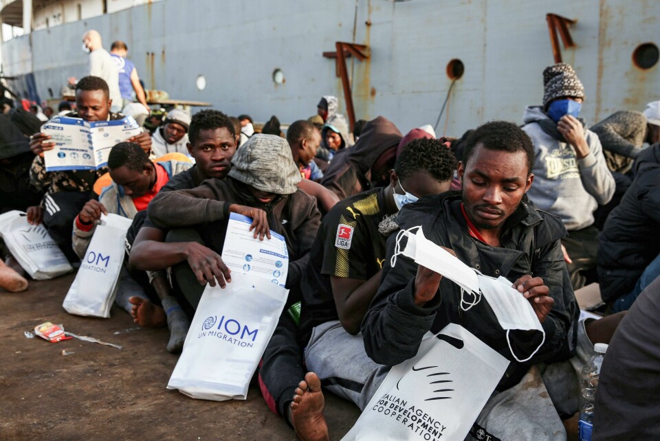 Migrants rescued off the coast of al-Khums, about 120 kilometres east of the capital, receive aid packages (including surgical masks for the COVID-19 coronavirus pandemic) as they sit on the pier in Tripoli's naval base on February 10, 2021. (Photo by - / AFP) Migrants rescued off the coast of al-Khums, about 120 kilometres east of the capital, receive aid packages (including surgical masks for the COVID-19 coronavirus pandemic) as they sit on the pier in Tripoli's naval base on February 10, 2021. (Photo by - / AFP)