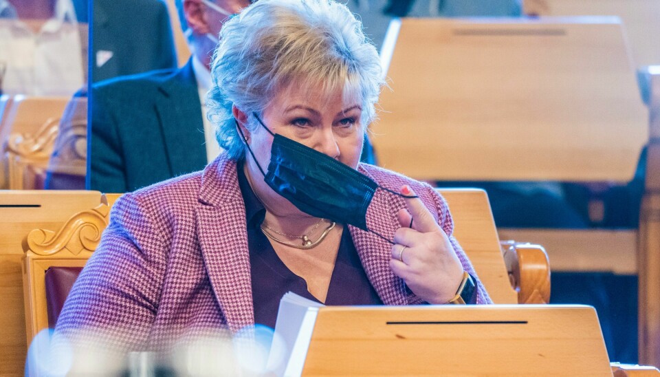Statsminister Erna Solberg tar av seg masken før redegjørelsen i Stortinget tirsdag.Foto: Håkon Mosvold Larsen / NTB