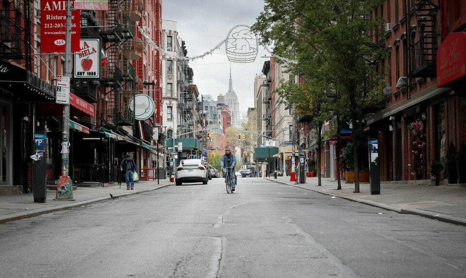 En syklist på tom gate med Empire State Building langt i bakgrunnen. I New York vil inngripende smittevernstiltak opprettholdes en stund til, mens det i flere steder ellers i USA er i ferd med å åpnes opp igjen.