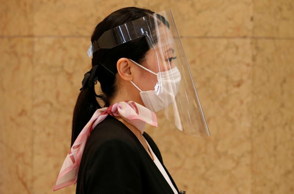 De ansatte ved Nihombashi Takashimaya i Tokyo må gå med maske og visir på jobb idet kjøpesenterte gjenåpnet for handlende.