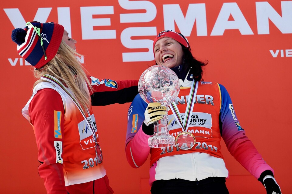 Therese Johaug (t.v.) og Marit Bjørgen ler på pallen etter verdenscuprenn i Oslo i 2014.