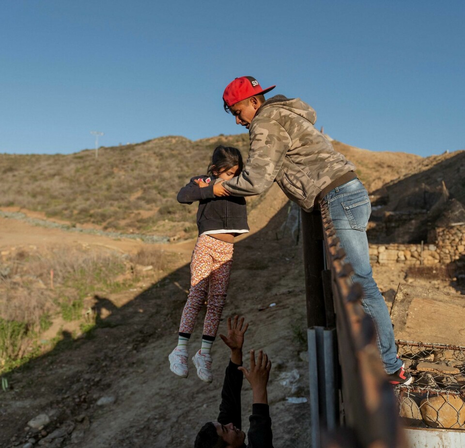 GJERDE: En migrant fra Honduras løfter datteren sin over grensegjerdet ved San Diego.FOTO: DANIEL OCHOA DE OLZA/NTB SCANPIX GJERDE: En migrant fra Honduras løfter datteren sin over grensegjerdet ved San Diego.FOTO: DANIEL OCHOA DE OLZA/NTB SCANPIX
