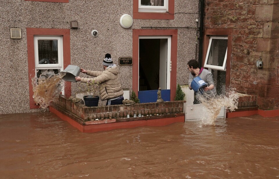 To menn forsøker å holde flomvannet unna i en bolig i Appleby-in-Westmorland i Cumbria i England søndag. Uværet har fått navnet Ciara i Storbritannia. Men try to control the flow of flood water, outside a property, in Appleby-in-Westmorland, as Storm Ciara hits the UK, in Cumbria, England, Sunday Feb. 9, 2020. Trains, flights and ferries have been cancelled and weather warnings issued across the United Kingdom as a storm with hurricane-force winds up to 80 mph (129 kph) batters the region. (Owen Humphreys/PA via AP)