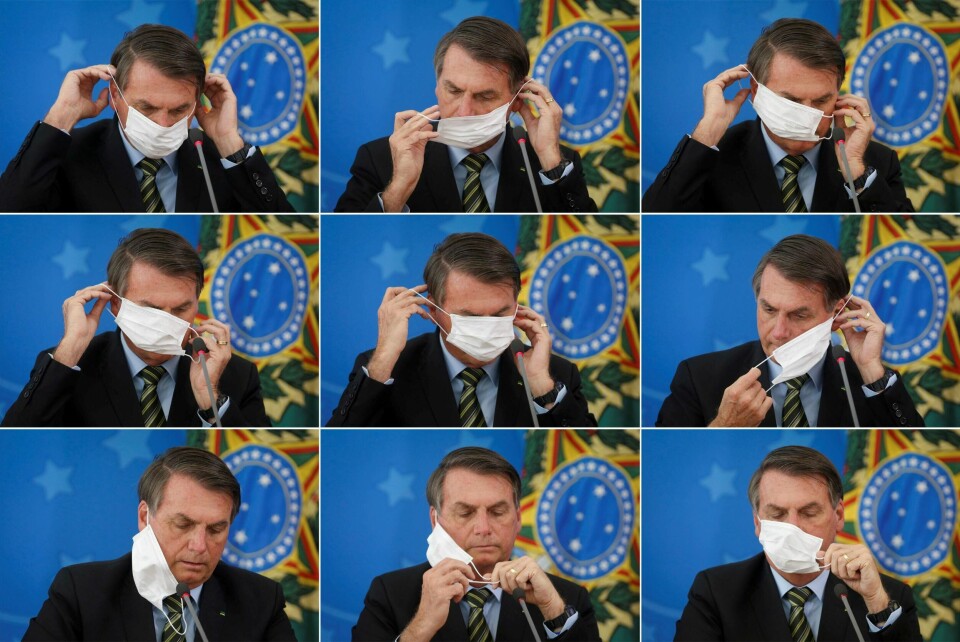 Brasils president Jair Bolsonaro strever med å få festa ansiktsmaska under en pressekonferanse om landets nye smitteverntiltak mot koronaviruset. Foto: Adriano Machado / Ntb Scanpix