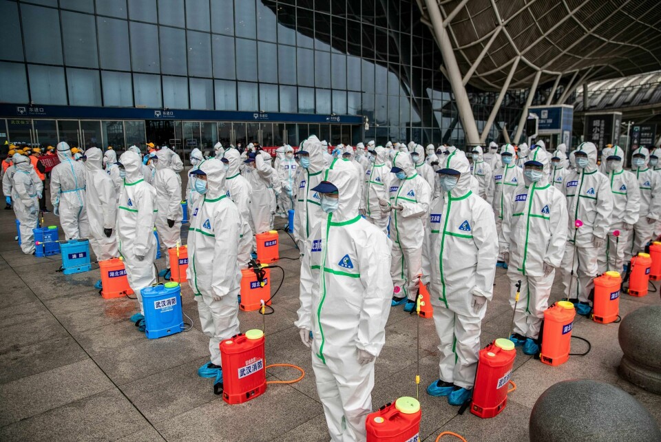 Smittevernarbeidere klare til å desinfisere togstasjonen i Wuhan tirsdag. Den kinesiske byen der koronapandemien startet gjør seg nå klare for å åpne opp og lette på de strenge smitteverntiltakene. Foto: Ntb Scanpix