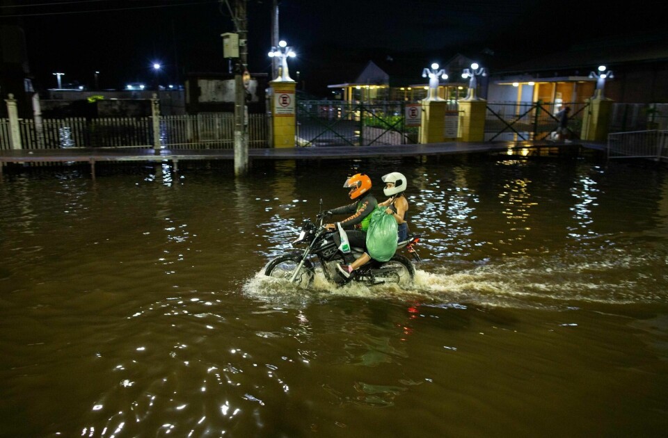 Folk prøver å komme seg fram på motorsykkel i den flomrammede byen Manaus i Amazonas i Brasil etter at elva Rio Negro har godt svært høyt over sine bredder. Vannstanden i elva Amazonas er også veldig høy. TOPSHOT - People ride on a motorbike along a flooded street in the city centre of Manaus, capital of the Brazilian Amazonas State, on May 31, 2021. - The water level of the Rio Negro, a tributary of the Amazon river, reached 29,97 metres, the same record level as in the 2012 flood season. Manaus and 35 other cities have decreed a state of emergency due to the overflowing of the river. (Photo by Michael DANTAS / AFP)