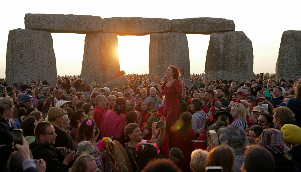 Årets lengste dag feires av tilskuere ved Stonehenge. Revelers gather at the ancient stone circle Stonehenge to celebrate the Summer Solstice, the longest day of the year, near Salisbury, England, Wednesday, June 21, 2023. Druids, pagans, hippies, local residents, tourists and costumed witches and wizards have gathered around a prehistoric stone circle on a plain in southern England to express their devotion to the sun. (AP Photo/Kin Cheung)