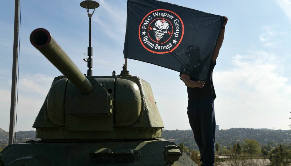 En mann poserer foran et Wagner-flagg i Donetsk. En mann poserer foran en Wagner-flagg i Donetsk.