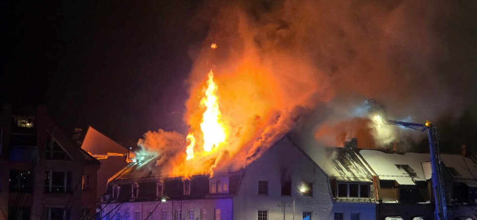 Natt til fredag begynte det å brenne i et bygg i Fredrikstad sentrum. Gjester og ansatte ved Hotel Fredrikstad, som er nærmeste nabo, er evakuert. Bildet viser bygningen som brenner i Fredrikstad. Høye flammer slynger seg opp av taket.