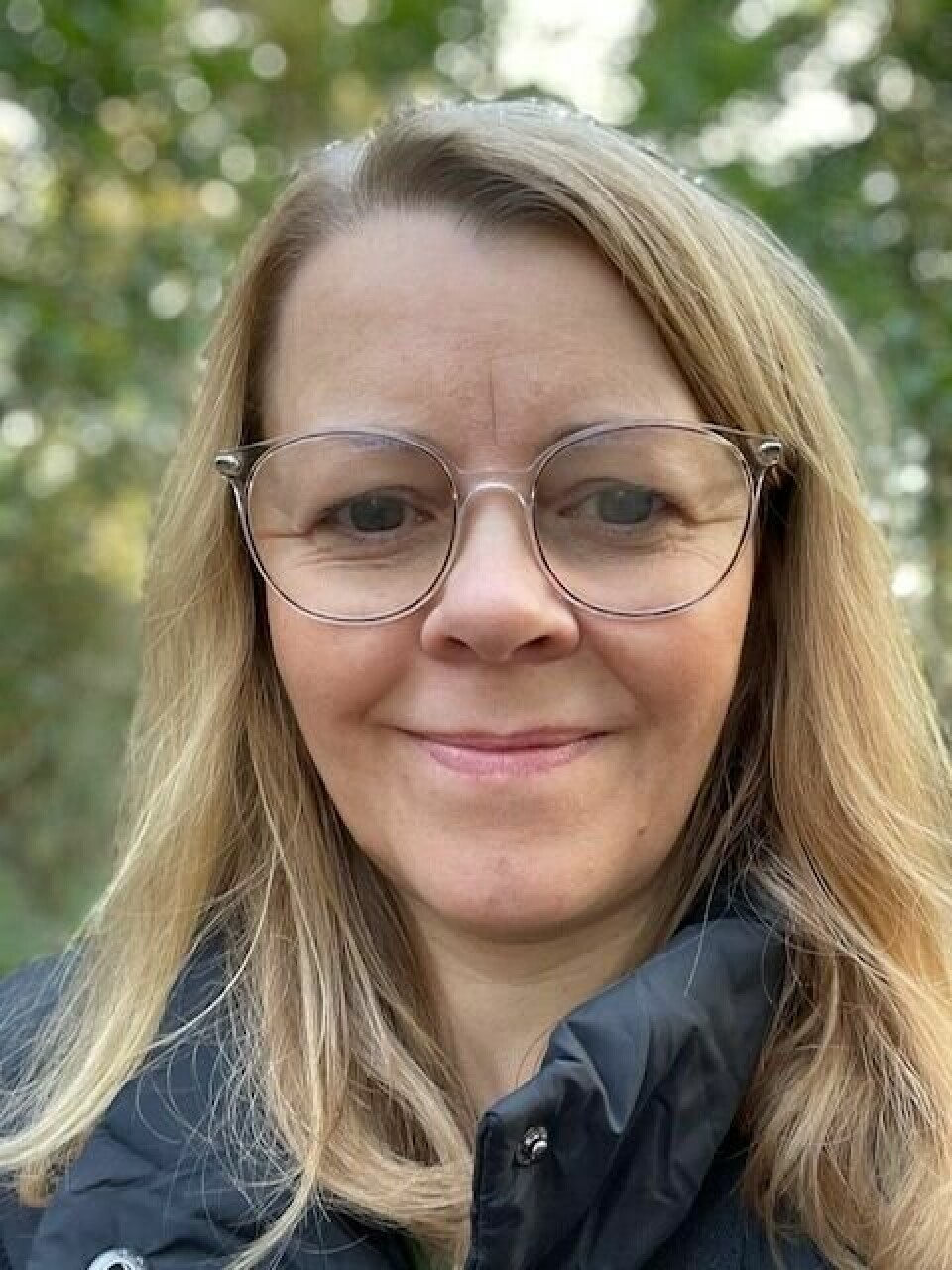 Daghild Tonning Kvinne med skandinavisk utseendet, blond, briller, smiler med munnen lukket.