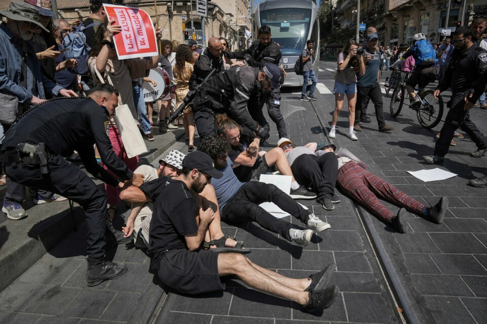 Politi forsøker å fjerne demonstranter som sperrer for trikken i Jerusalem. Politiet fjerner israelske demonstranter som sperrer en gate i Jerusalem i protest mot at regjeringen ikke inngår avtale med Hamas om våpenhvile og løslatelse av gislene. Foto: Mahmoud Illean / AP / NTB