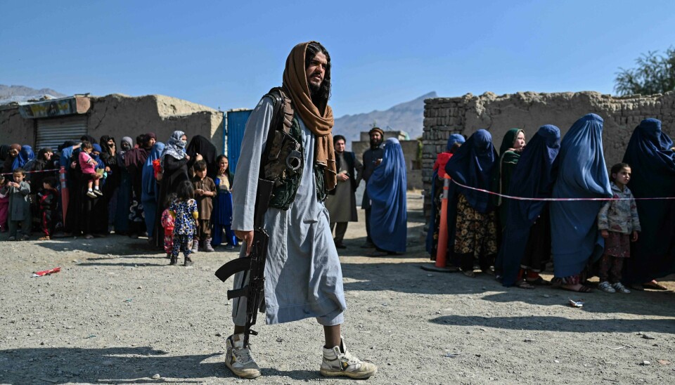 En Taliban-soldat holder vakt mens afghanske kvinner står i matkø hos Verdens matvareprogram i utkanten av Kabul tidligere i november. En Taliban-soldat holder vakt mens afghanske kvinner står i matkø hos Verdens matvareprogram i utkanten av Kabul tidligere i november.