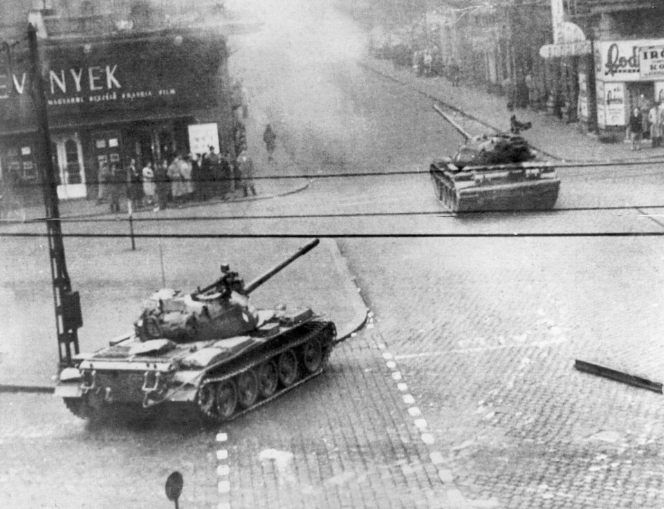 Sovjetiske tanks i den ungarske hovedstaden Budapest under oppstanden i 1956. Soviet-built tanks wheel into action in a smoke-filled Budapest street in Hungary's flaring revolution against communist satellite government, Oct. 27, 1956. Citizens stand close to building fronts to stay out of the line of fire. Many Hungarian Army units reportedly have gone over to the rebels in fighting against police and units of the Soviet Red Army. (AP Photo)