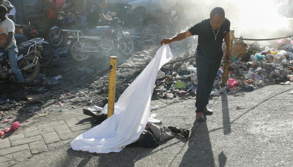 En person løfter på et klede som er lagt over ett av ofrene etter mandagens skyting i Petion-Ville i Port-au-Prince. En person løfter på et klede som er lagt over ett av ofrene etter mandagens skyting i Petion-Ville i Port-au-Prince. Foto: Odelyn Joseph / AP / NTB