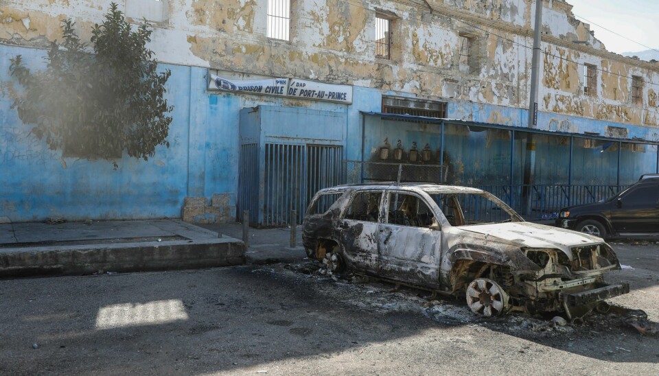 En utbrent bil utenfor hovedfengselet i Port-au-Prince etter at bevæpnede gjenger stormet fengselet og hundrevis av fanger rømte. Bildet viser en utbrent bil utenfor et fengsel i Haiti, der flere innsatte flyktet i løpet av natten. Foto: Odelyn Joseph / AP / NTB