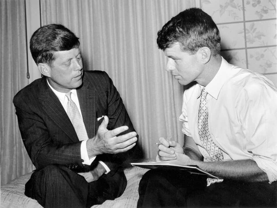 Brødrene John F. Kennedy og Robert F. Kennedy, far til RFK Jr., avbildet sammen i 1960. Massachusetts Sen. John F. Kennedy, left, compares notes with his brother and campaign manager, Robert Kennedy, on July 10, 1960 in an unknown location. The Senator is seeking the Democratic presidential nomination. (AP Photo)