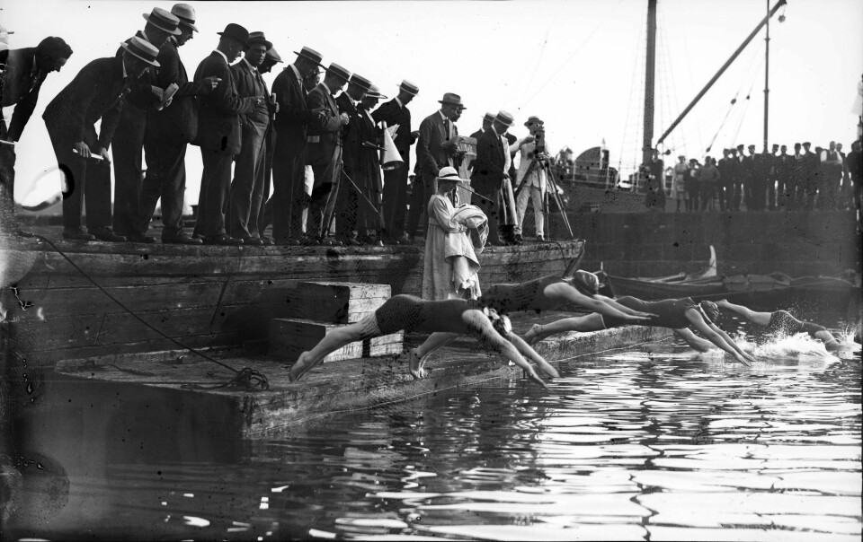 Svømmestevnet 1917 på Filipstad. Svømmerne stuper uti med badedrakt og beadehetter mens publikum med hatter følger med.
