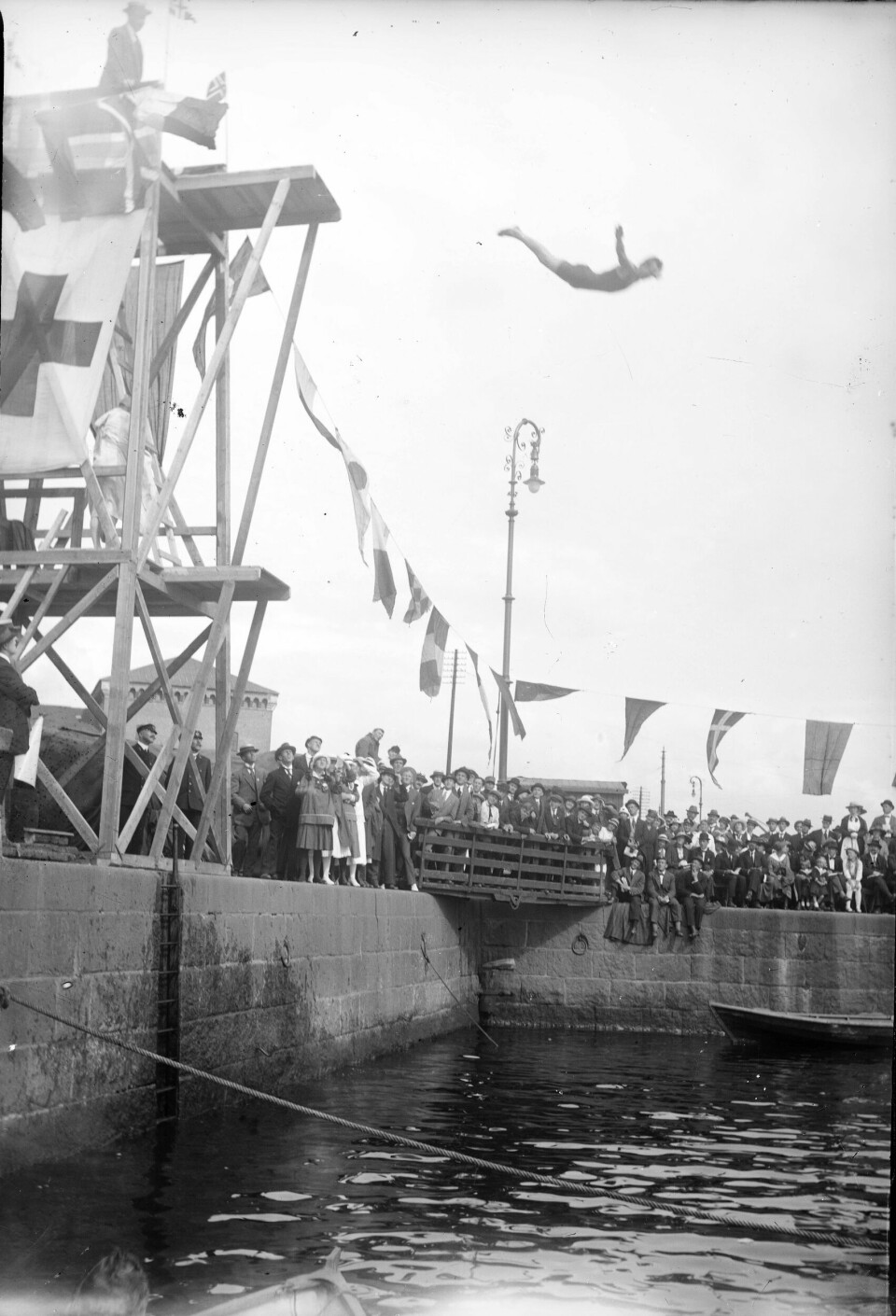 Svømmestevne 1916 på Filipstad En stuper er i svevet. Kaia er tettpakket med publikum.