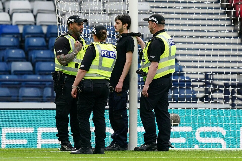 Skotsk politi snakker med demonstranten som hadde lenket seg fast til en målstolpe før avspark mellom Skottland og Israel på Hampden Park. Skotsk politi snakker med demonstranten som hadde lenket seg fast til en målstolpe før avspark mellom Skottland og Israel på Hampden Park. Foto: Jane Barlow / PA / AP / NTB