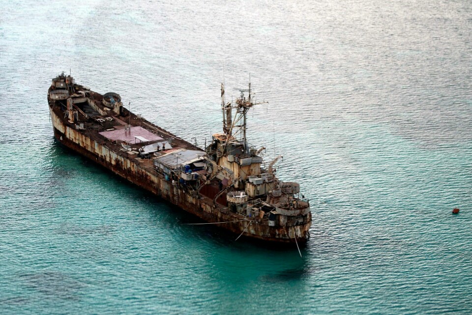 Et flyfoto fra 2015, som viser skipsvraket BRP Sierra Madre. FILE - This areral photo taken through a glass window of a military plane shows the dilapidated Sierra Madre ship of the Philippine Navy anchored near Ayungin Shoal with Filipino soldiers onboard to secure perimeter in the Spratly Islands in the South China Sea on May 11, 2015. Chinese coast guard ships blocked and used water cannons on two Philippine supply boats heading to a disputed shoal occupied by Filipino marines in the South China Sea, provoking an angry protest against China and a warning from the Philippine government that its vessels are covered under a mutual defense treaty with the U.S., Manila’s top diplomat said Thursday, Nov. 18, 2021. (Ritchie B. Tongo/Pool Photo via AP, File)