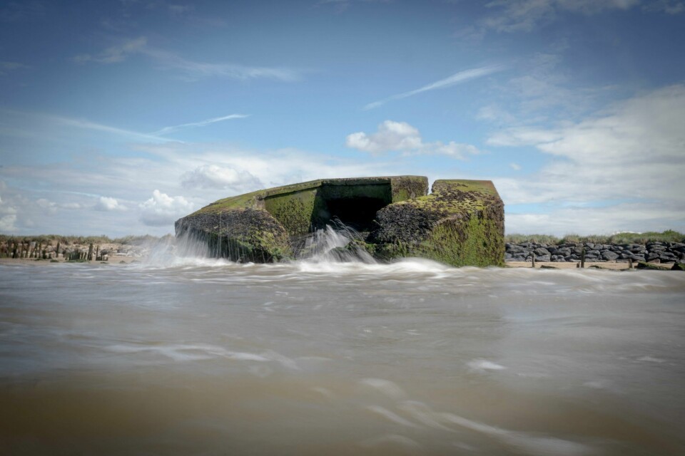 Bølger skyller over en bunker i Normandie, på stranden som fikk kallenavnet Juno under D-dagen i 1944. (FILES) This photograph shows a partially submerged bunker (Blockhaus) from the Atlantic Wall near Asnelles, Normandy, northern France on May 16, 2024, which was given the code name 'Juno Beach' during the Allied D-Day landings in 1944. The Atlantic Wall, made up of bunkers or blockhaus was ordered by Nazi Germany's leader Adolf Hitler to be built and between 1942 and 1944, stretched some 5000km from northern Norway to the Franco-Spanish border to defend occupied territories from sea borne attack. 15,000 of them were planned to be built, but due to insufficient manpower and material, only about half of them were completed. (Photo by Olivier MORIN / AFP)