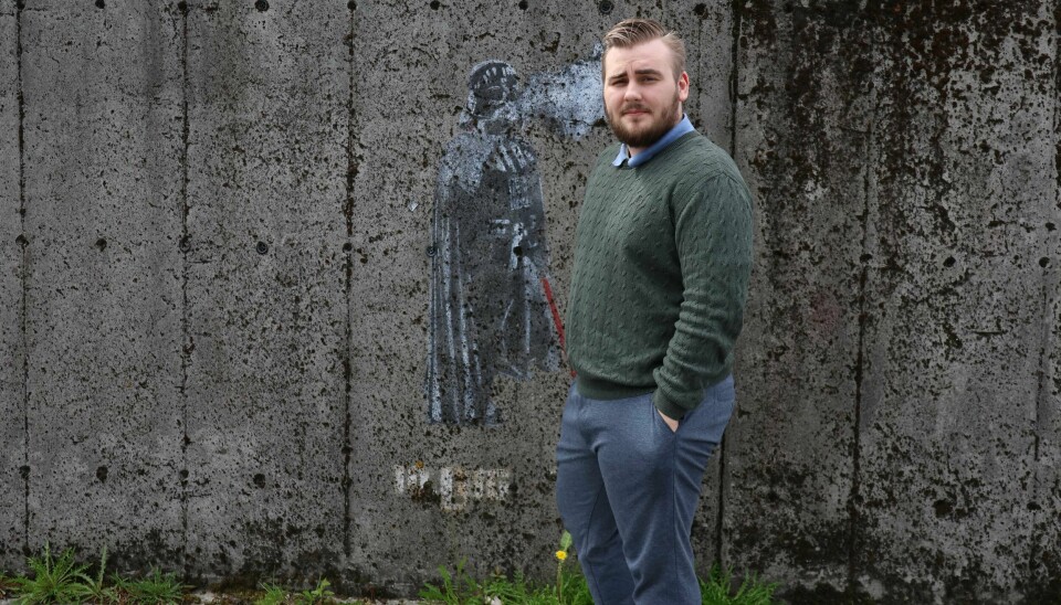 Elias Fanebust ved siden av et verk av gatekunstneren 10Dig som dukket opp utenfor e-sigarettbutikken hans i Åsane. Elias Fanebust, daglig leder i Dampshop, foran gatekunst av 10Dig