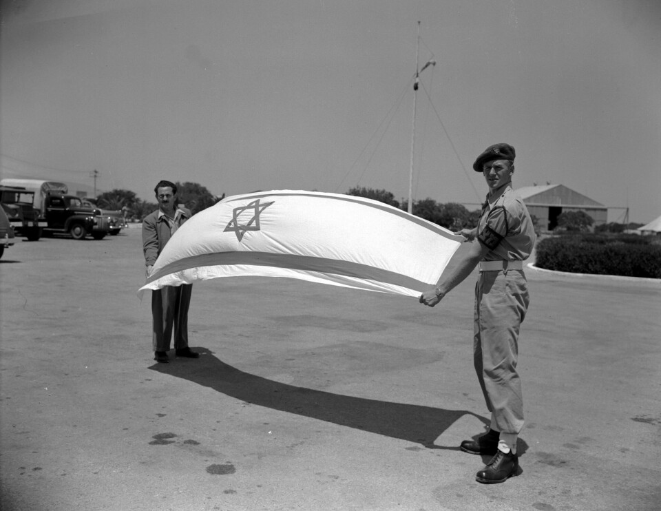 En politisoldat fra den paramilitære gruppa Haganah skal heise det israelske flagget i Haifa i mai 1948. .
