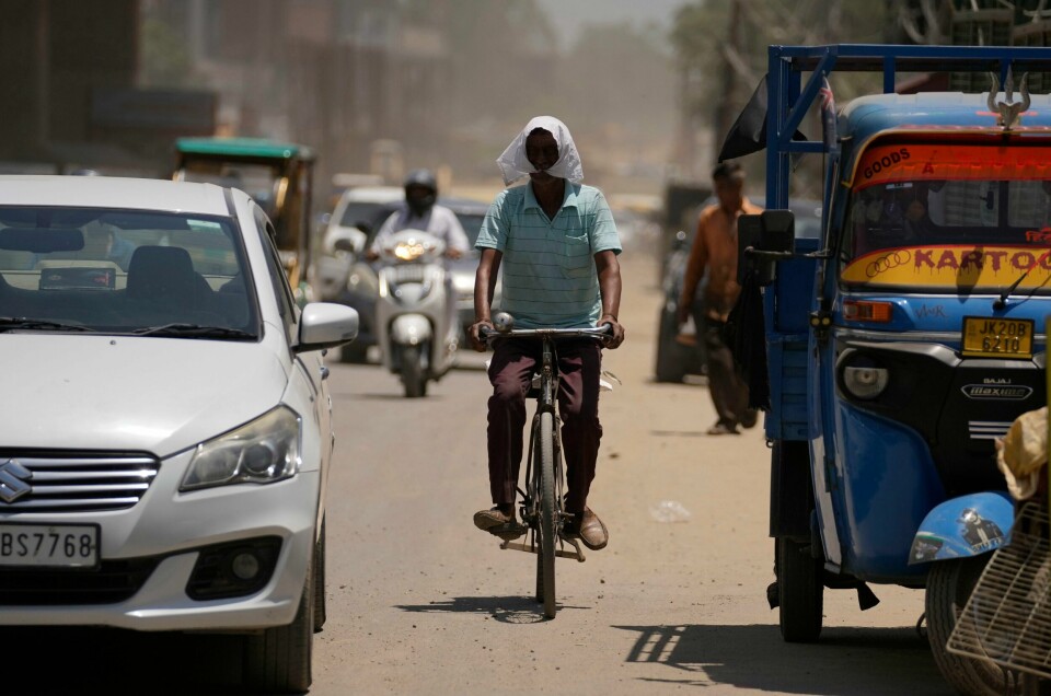 Akrivfoto fra Jammu i India. India koker, denne mannen har dekket til hodet i et forsøk på å skjerme seg fra den brennende solen. Men temperaturrekorden på 52,9 grader som ble målt onsdag, kan være feil. Foto: AP / NTB