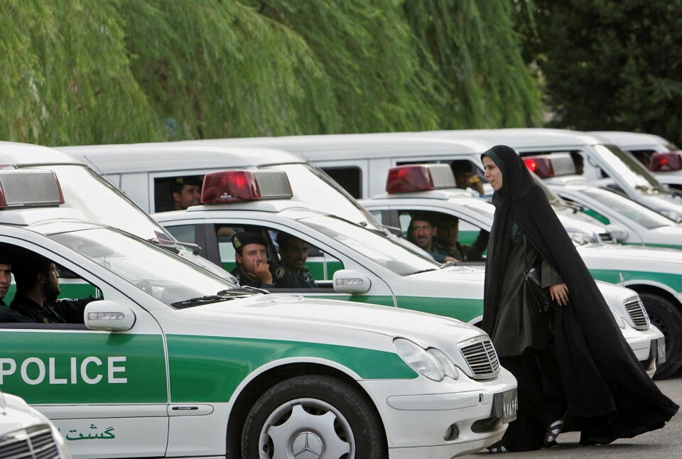 Et kvinnelig medlem av det iranske moralpolitiet går mellom biler som tilhører politistyrken i Teheran i 2007. Et kvinnelig medlem av det iranske moralpolitiet går mellom biler som tilhører politistyrken i Teheran i 2007.