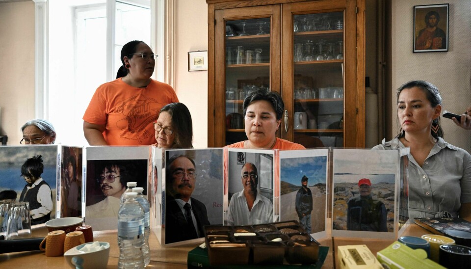 Leder Aluki Kotierk (2. fra venstre), Tanya Tungilikand (2. fra høyre) og andre medlemmer av inuittdelegasjonen viste bilder av overgrepsofre under et besøk i Lyon i september. En delegasjon av kanadiske inuitter på besøk i Lyon, sitter rundt et møtebord og viser frem bilder.