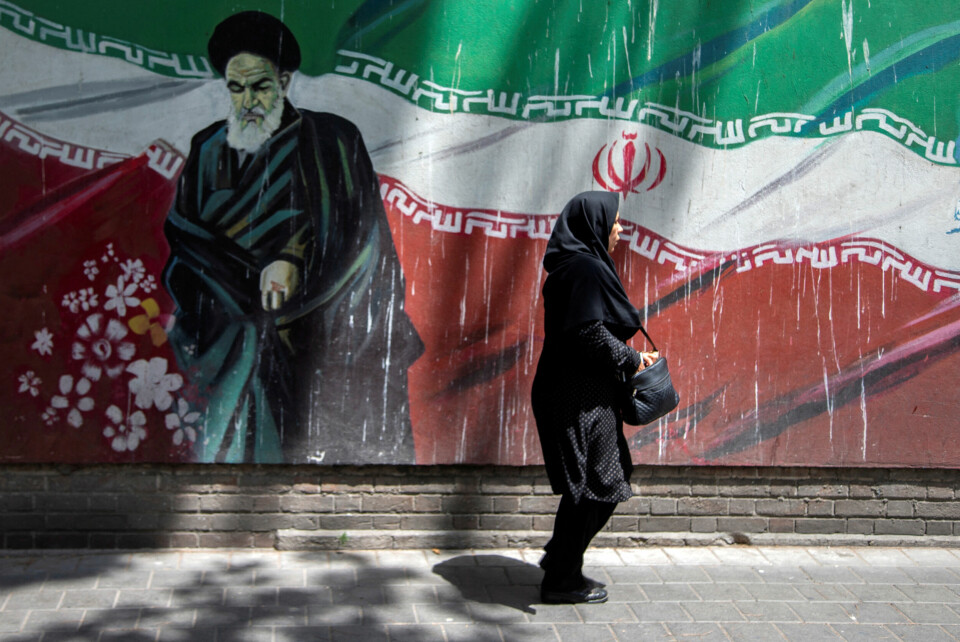 En iransk kvinne går foran et veggmaleri av tidligere leder ayatolla Ruhollah Khomeini i Tehran i 2019. En iransk kvinne går foran et veggmaleri av tidligere leder ayatolla Ruhollah Khomeini i Tehran.