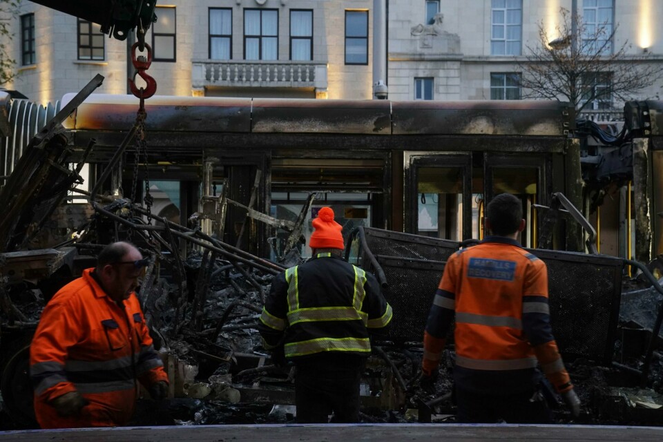 Mannskaper rydder bort restene av en utbrent trikk i en gate i Dublin fredag morgen. Mannskaper rydder bort restene av en utbrent trikk i en gate i Dublen fredag morgen. Foto: Brian Lawless / AAP / NTB